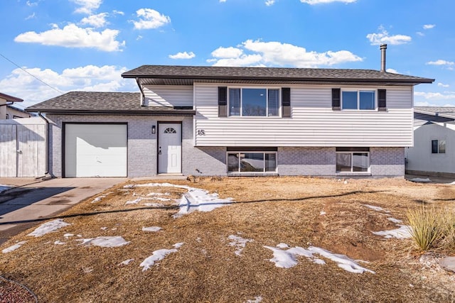 split level home featuring a garage, concrete driveway, and brick siding