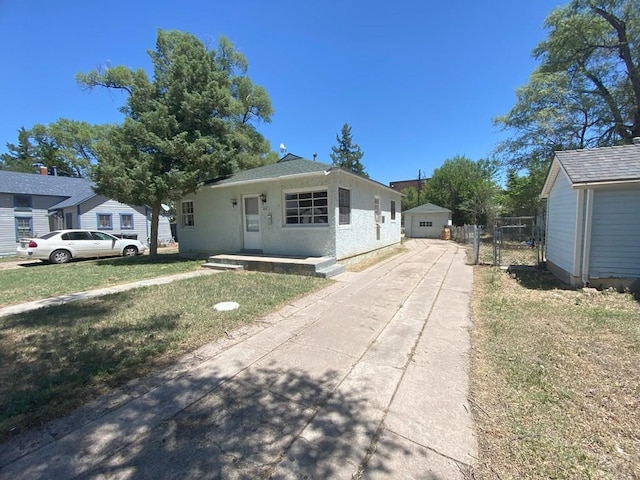 bungalow with a front yard, fence, a detached garage, and stucco siding