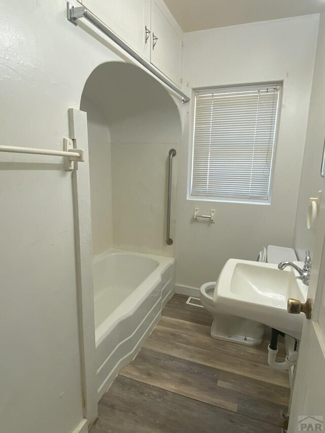 bathroom featuring bathtub / shower combination, visible vents, toilet, wood finished floors, and baseboards