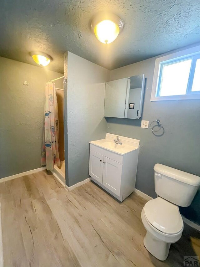 15 E 8th St, La Junta, CO 81050 - bathroom featuring wood finished floors, a textured ceiling, vanity, and a stall shower