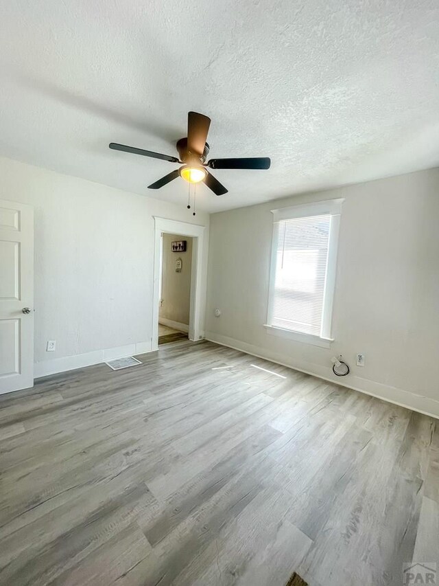 15 E 8th St, La Junta, CO 81050 - empty room with a textured ceiling, wood finished floors, and ceiling fan