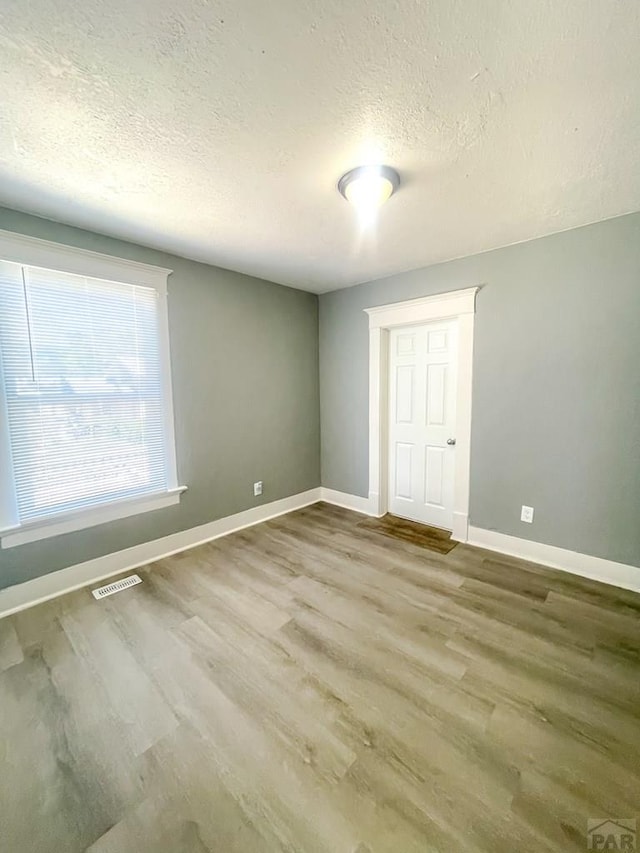 15 E 8th St, La Junta, CO 81050 - unfurnished bedroom with a textured ceiling and wood finished floors