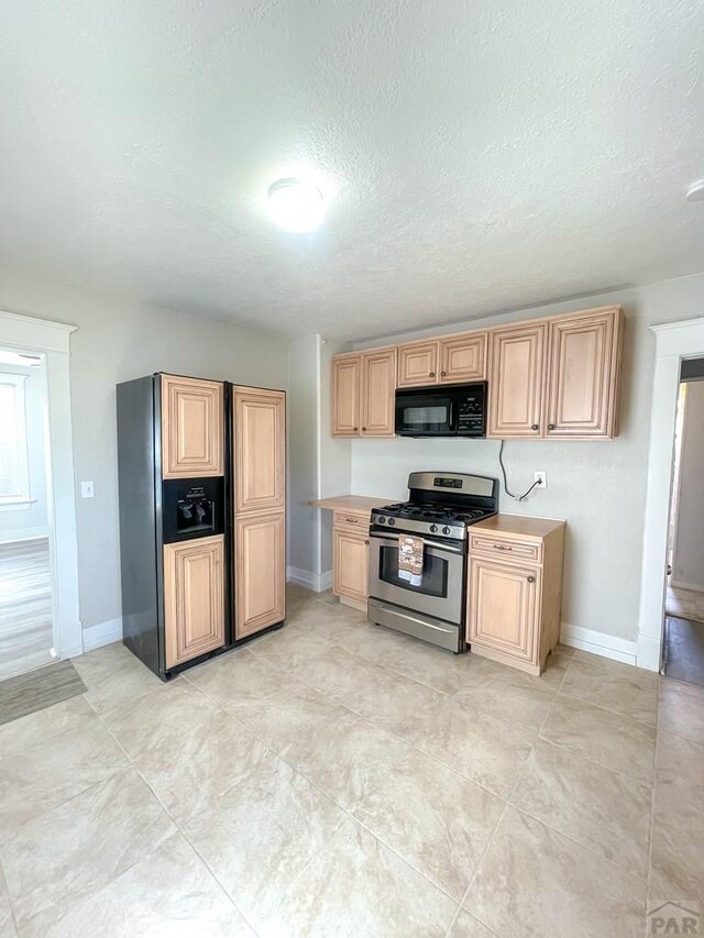 15 E 8th St, La Junta, CO 81050 - kitchen featuring gas range, black microwave, a textured ceiling, light brown cabinetry, and light countertops