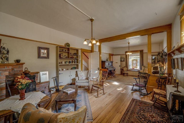 314 S Main St, La Veta, CO 81055 - living room featuring radiator, a brick fireplace, light wood-style flooring, and decorative columns