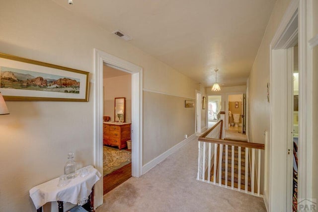 314 S Main St, La Veta, CO 81055 - hallway with light colored carpet, baseboards, visible vents, and an upstairs landing