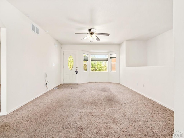 carpeted spare room featuring ceiling fan, baseboards, and visible vents