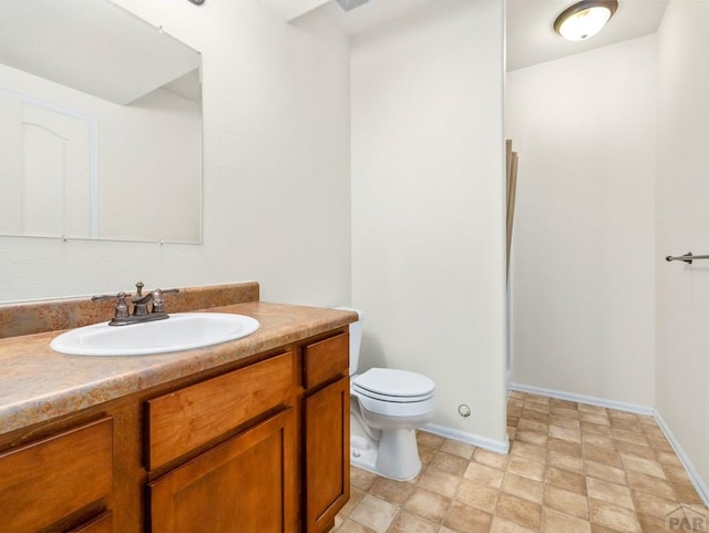 bathroom with baseboards, toilet, and vanity