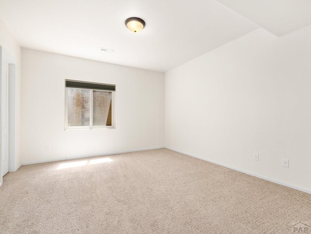empty room featuring light colored carpet and baseboards