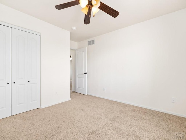 unfurnished bedroom with carpet, visible vents, a closet, baseboards, and ceiling fan