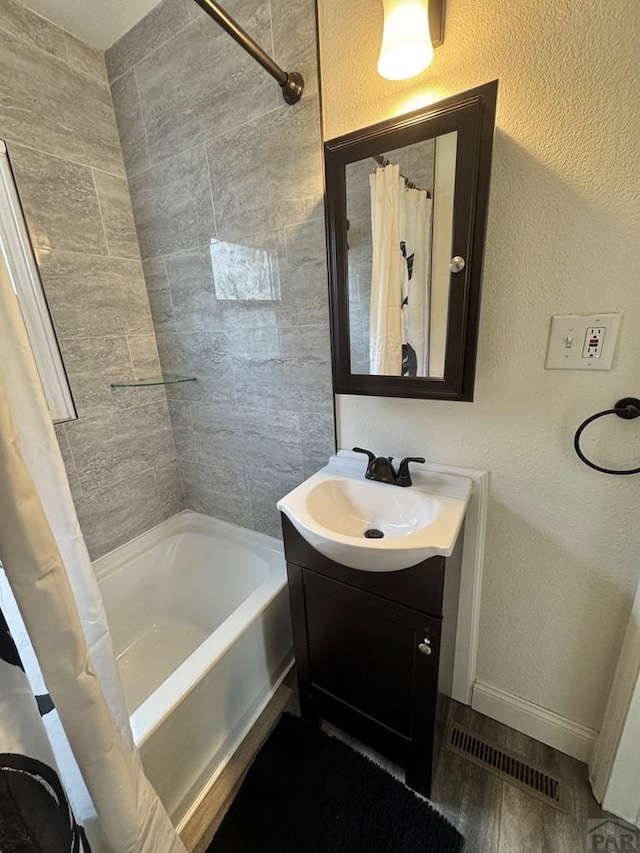 bathroom with visible vents, baseboards, a textured wall, shower / bathtub combination with curtain, and vanity