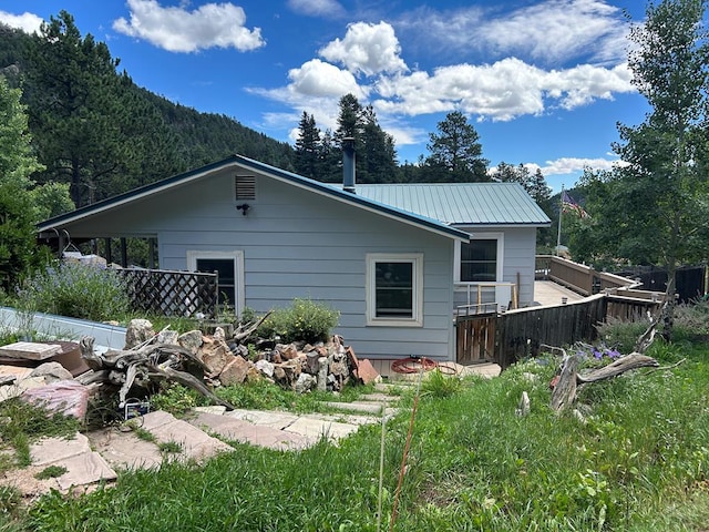 rear view of property featuring a mountain view, fence, and metal roof