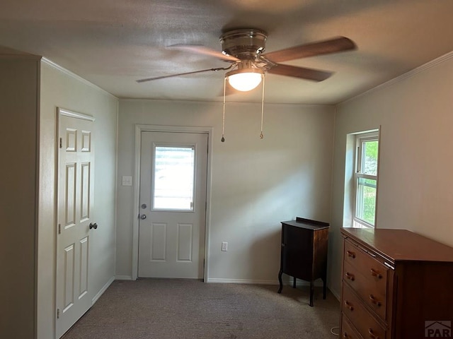 doorway featuring light colored carpet, crown molding, baseboards, and ceiling fan