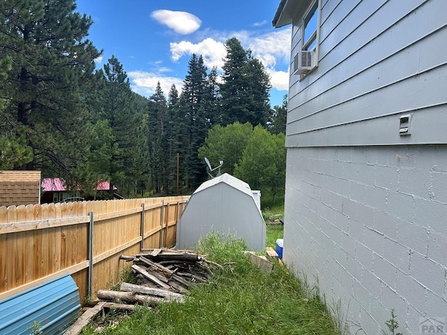 view of yard featuring a storage shed, fence, cooling unit, and an outdoor structure