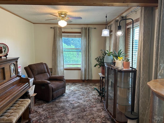 living area with baseboards, a ceiling fan, and crown molding