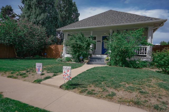 view of front of property with roof with shingles, fence, a porch, and a front yard