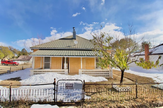 view of front of property featuring covered porch, metal roof, a fenced front yard, and stucco siding