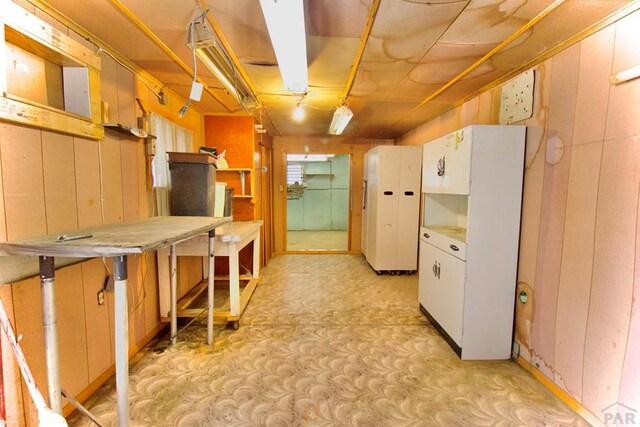 kitchen with a breakfast bar, decorative light fixtures, light countertops, wood walls, and white cabinetry