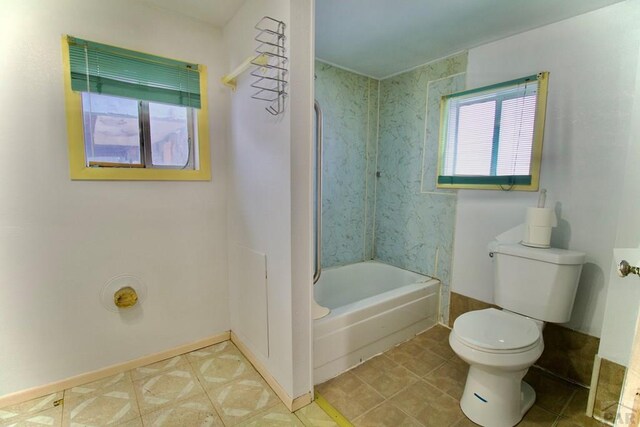 bathroom with toilet, baseboards, a wealth of natural light, and bathing tub / shower combination