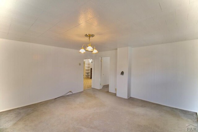 carpeted empty room with a chandelier