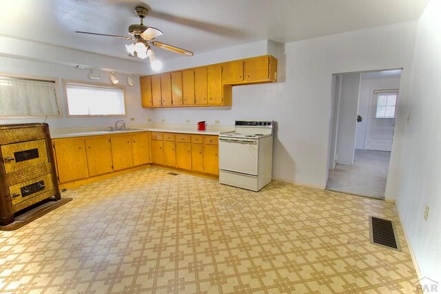 kitchen featuring light floors, white electric range oven, light countertops, visible vents, and a sink