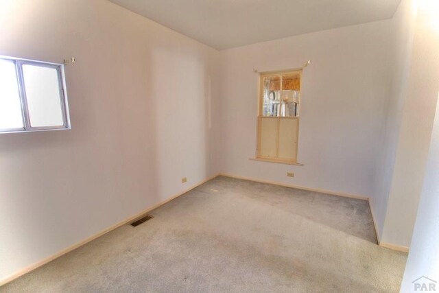 empty room with carpet flooring, visible vents, and baseboards