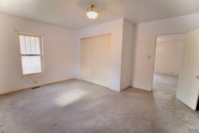 spare room featuring light colored carpet and visible vents