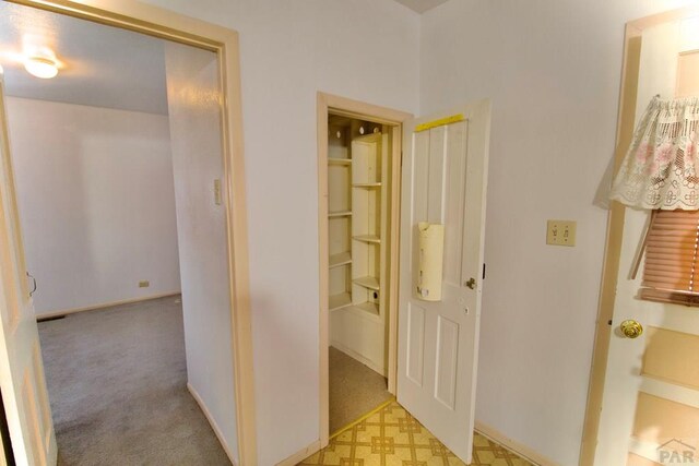 hall featuring light floors and baseboards