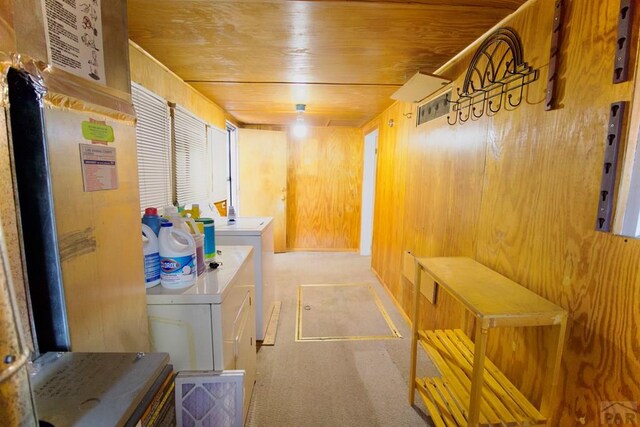 mudroom featuring wooden ceiling, wood walls, and washing machine and clothes dryer