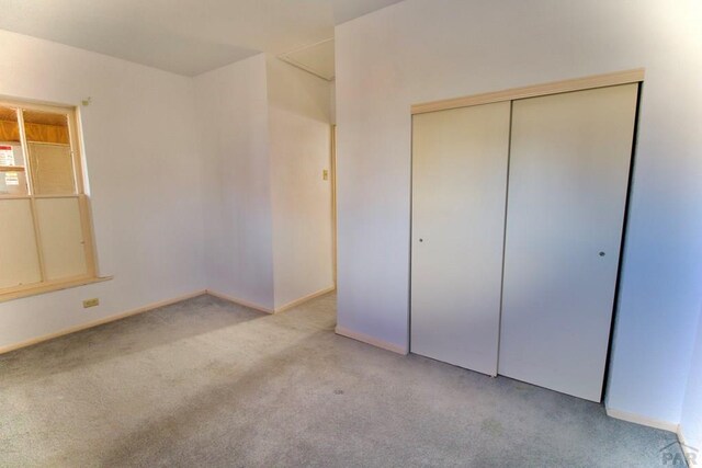 unfurnished bedroom with light carpet and a closet