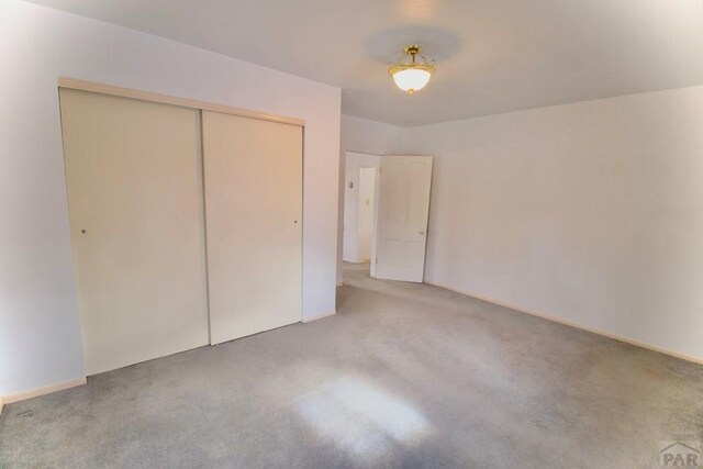 unfurnished bedroom featuring a closet and light carpet