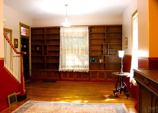 sitting room with wood finished floors, visible vents, a textured ceiling, and stairs