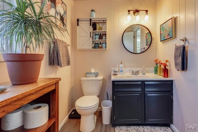 bathroom with toilet, wood finished floors, and vanity