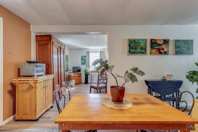 dining area featuring light wood-style floors, a toaster, and baseboards