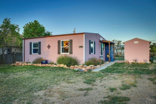 view of front of house featuring an outbuilding, a shed, a front lawn, and fence