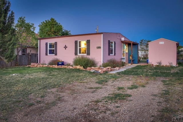 view of front of property featuring an outbuilding, fence, a front lawn, and a storage unit