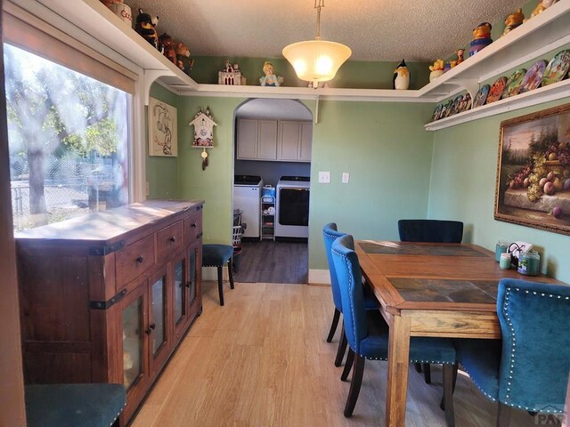 dining room with light wood-style floors, a textured ceiling, and washer and dryer