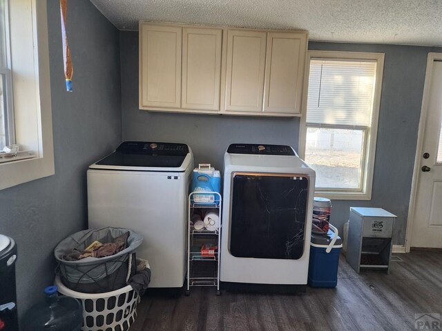 clothes washing area with a textured ceiling, separate washer and dryer, dark wood-type flooring, and cabinet space