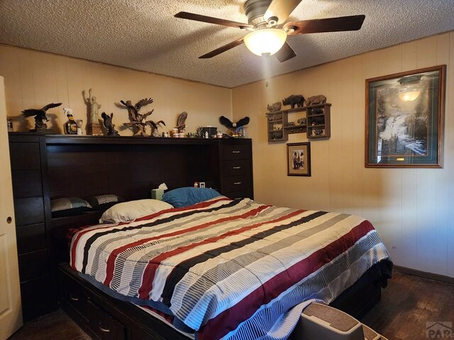 bedroom featuring dark wood-style floors, a textured ceiling, and a ceiling fan