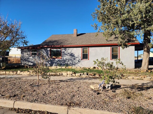 view of front facade with roof with shingles, fence, and a chimney