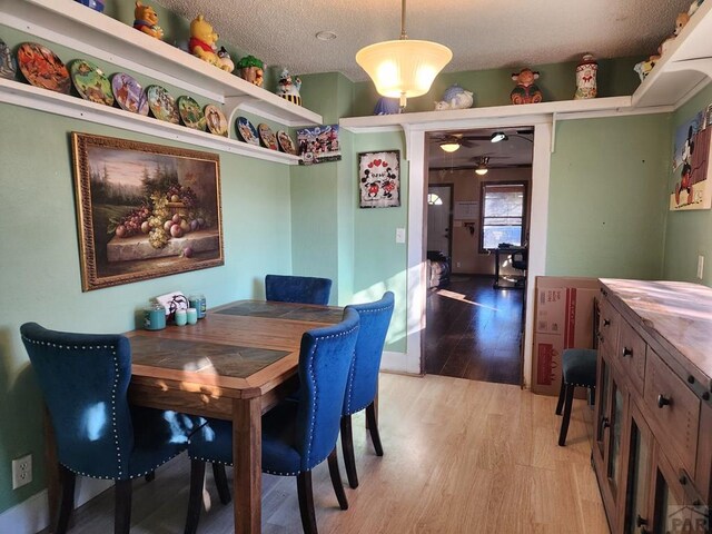 dining room featuring a textured ceiling, ceiling fan, and wood finished floors