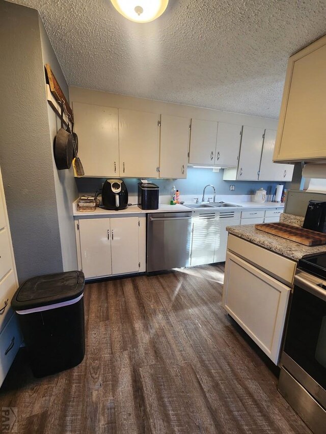 kitchen with stainless steel appliances, light countertops, a sink, and dark wood-style floors