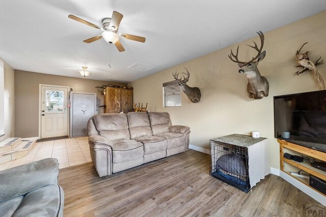 living room featuring a ceiling fan, wood finished floors, attic access, and baseboards