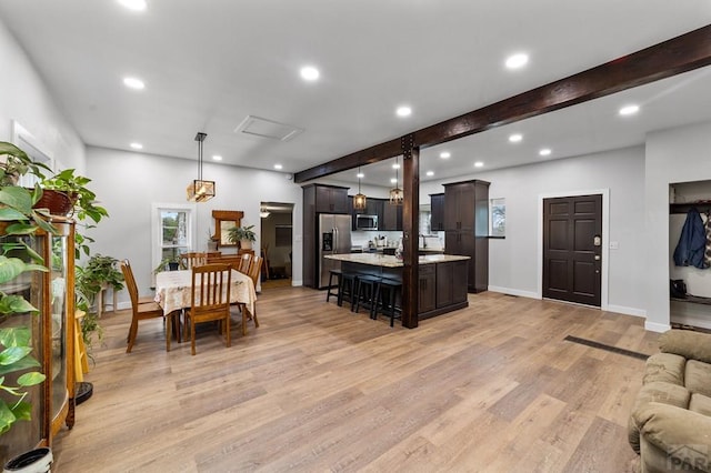 kitchen with an island with sink, appliances with stainless steel finishes, open floor plan, decorative light fixtures, and light countertops