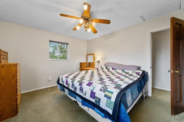 bedroom with attic access, dark colored carpet, a textured ceiling, and baseboards