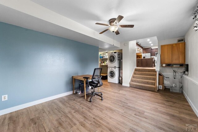 office space featuring stacked washing maching and dryer, baseboards, and light wood finished floors