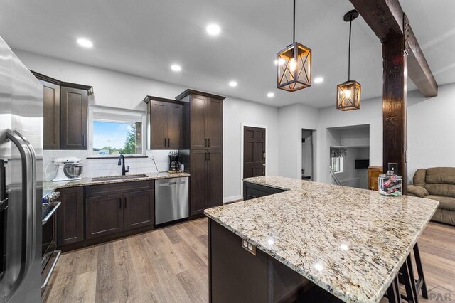 kitchen featuring a center island, hanging light fixtures, light wood-style flooring, appliances with stainless steel finishes, and open floor plan