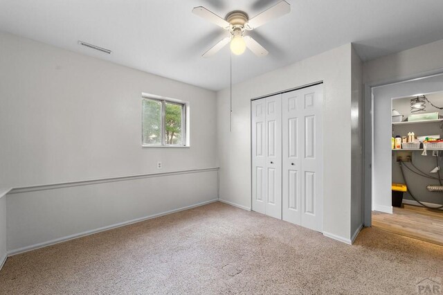 unfurnished bedroom with baseboards, visible vents, light colored carpet, ceiling fan, and a closet