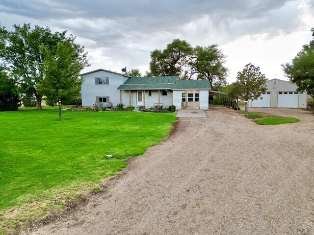 view of front of home featuring a garage, a front yard, and an outbuilding