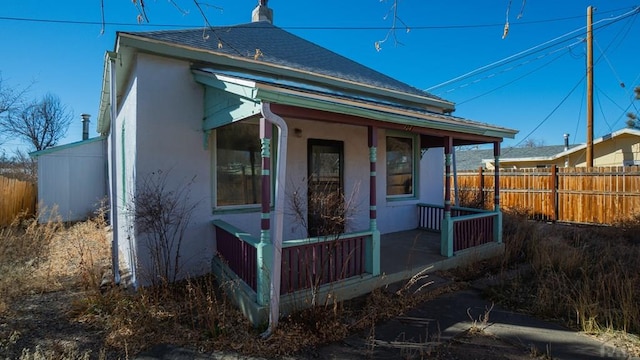 509 Walsen Ave, Walsenburg, CO 81089 - view of front of house with covered porch, fence, a chimney, and stucco siding