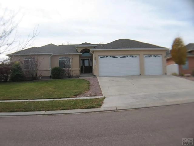 single story home with driveway, a front yard, an attached garage, and stucco siding